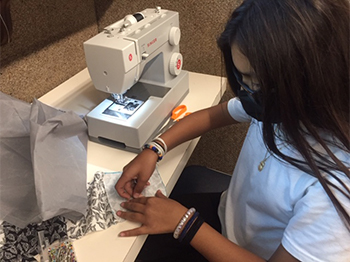 girl at sewing machine working on project